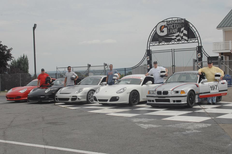 group of racecar drivers next to their cars